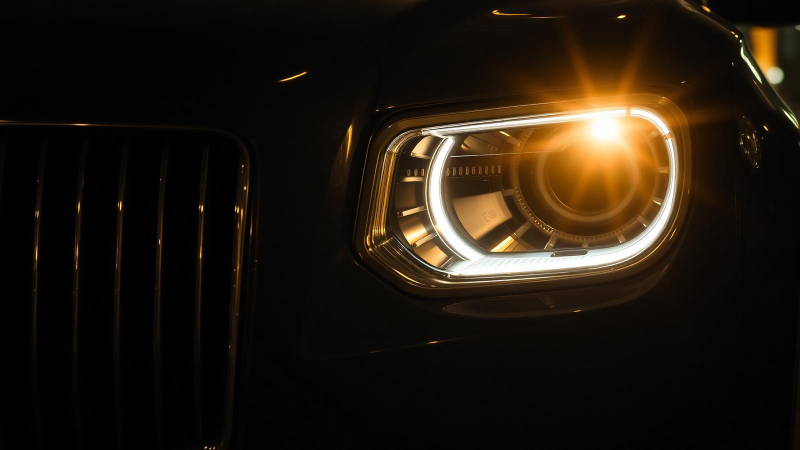 Illuminated luxury car headlight and grille detail